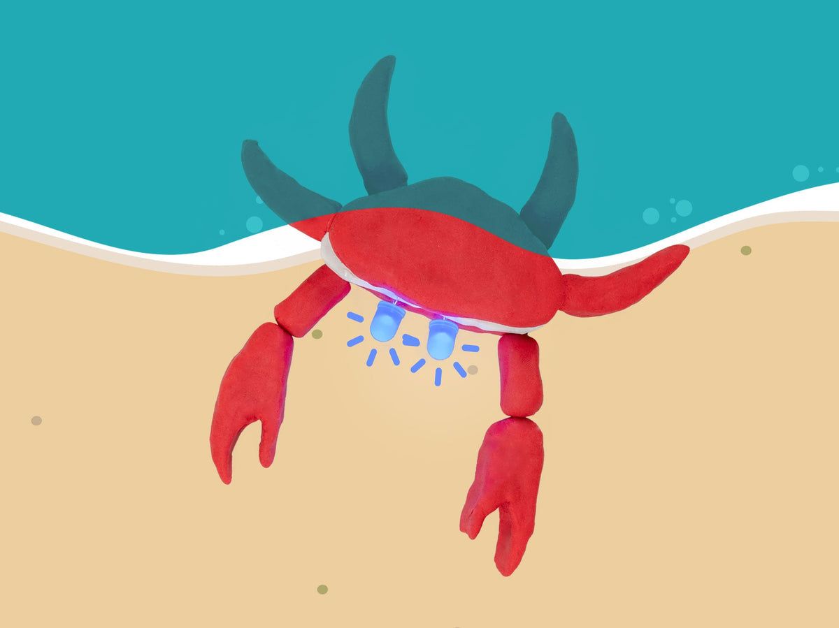 Red dough crab with glowing LED eyes on a beach