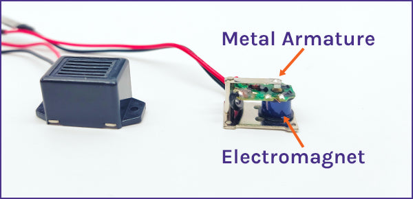A mechanical buzzer opened up to show its metal armature and electromagnet
