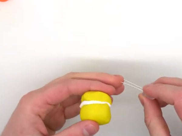 Hands pressing two yellow dough halves together with white insulating dough between them