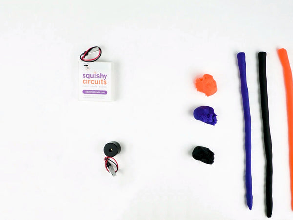 Long strips of purple, black and orange dough next to the buzzer