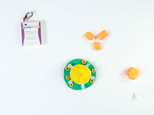 UFO next to three orange dough balls for the landing gear